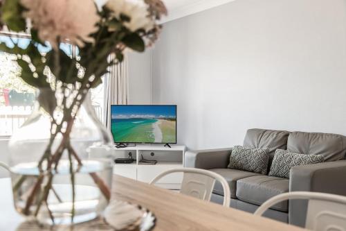 a living room with a table with a vase of flowers at Apartment 5B in Lennox Head