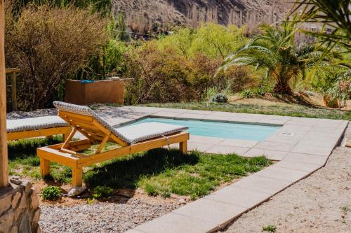 a wooden bench sitting next to a swimming pool at Piuquenes Lodge - Cabañas, Viñedos y estrellas en Horcón, Valle de Elqui in Horcon