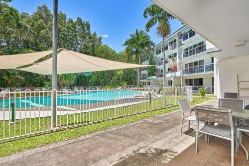 a patio with a table and chairs and a pool at Spindle Cowrie Apartments Palm Cove in Palm Cove