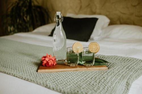 una botella y dos vasos en una bandeja en una cama en Castillo Tambor Resort & Restaurant en Tambor