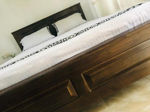 a wooden bed with white pillows on it at Royal Resort in Weligama