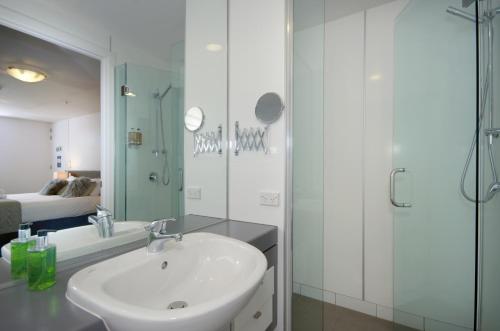 a white bathroom with a sink and a shower at Absolute Lake Front Luxury- 2 bedroom apartment in Queenstown