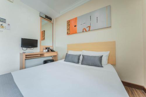 a bedroom with a large white bed and a tv at Hotel 81 Joy in Singapore