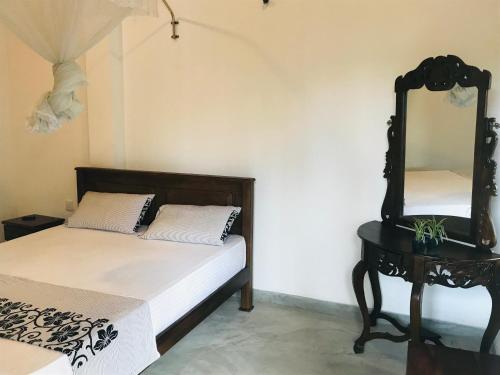 a bedroom with a bed and a mirror on a table at Royal Resort in Weligama