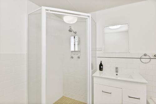 a white bathroom with a shower and a sink at Ocean Palms Unit 1 in The Entrance
