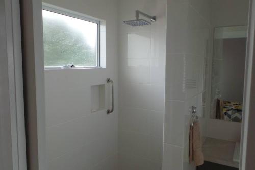 ein weißes Bad mit einer Dusche und einem Fenster in der Unterkunft Southern Comfort in Goolwa North