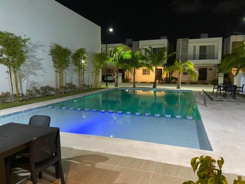 a swimming pool at night with a table and chairs at Casa Rosa Smart House in Playa del Carmen