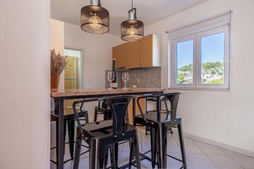 a kitchen with a bar with black stools at Apartments Perfect place in Hvar