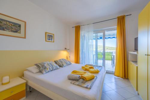 a bedroom with a large white bed with yellow curtains at Apartments Perfect place in Hvar