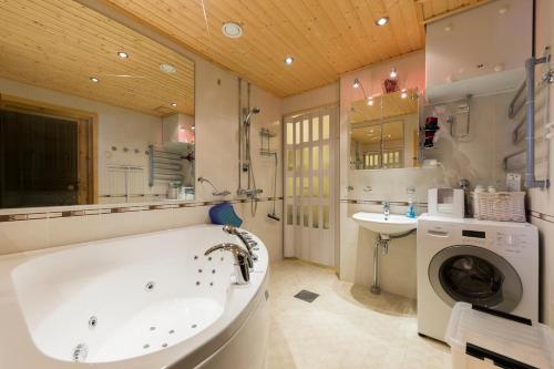 a bathroom with a tub and a sink and a washing machine at LevinSatu: SeLevi and TaLevi Apartments in Levi