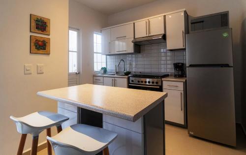 a kitchen with a refrigerator and a counter with stools at Casa Rosa Smart House in Playa del Carmen