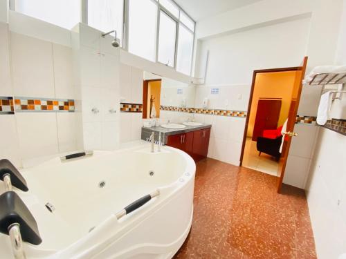 a large white bathroom with a tub and a sink at Hotel Las Palmeras in Huacho