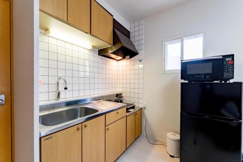 a kitchen with a sink and a black refrigerator at Sapporo Residential Juno in Sapporo