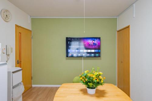 a room with a table with a tv on the wall at Sapporo Residential Juno in Sapporo