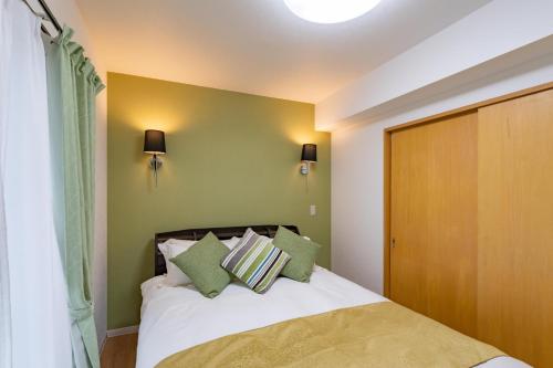 a bedroom with a bed with green walls at Sapporo Residential Juno in Sapporo