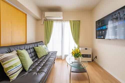a living room with a leather couch and a glass table at Sapporo Residential Juno in Sapporo