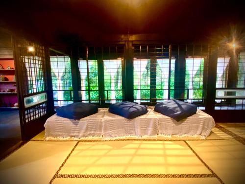 1 cama con 4 almohadas en una habitación con ventanas en Traditional house, Blue moon villa, 古民家 蒼月庵 en Kimitsu