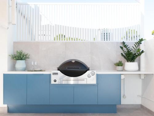 a kitchen with blue cabinets and a grill at Bali Hai Apartments Noosa in Noosa Heads