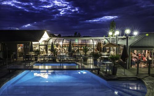 un hotel con piscina por la noche en Hotel Du Golf en Saint-Étienne