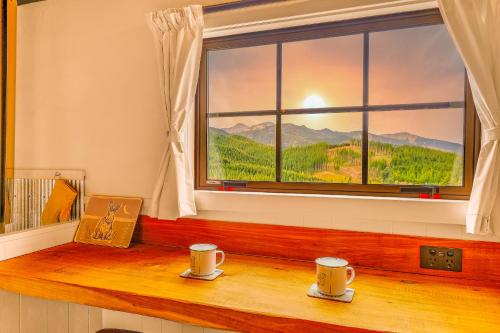 two coffee cups sitting on a wooden window sill at The Shepherds Hut - boutique retreat. in Hanmer Springs