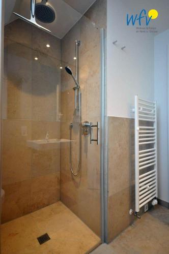 a shower with a glass door in a bathroom at Achterhus - Ferienwohnung Inseltraum in Juist