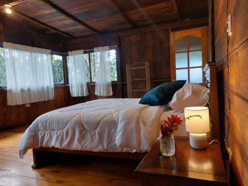 een slaapkamer met een bed en een tafel met een lamp bij The Temple II, Mindo in Mindo