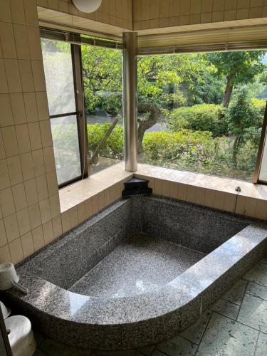 a large bath tub in a bathroom with a window at 地中海の家 in Futo