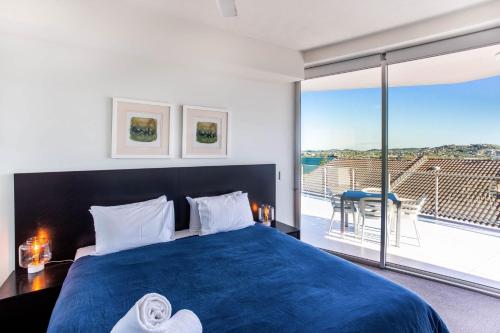 1 dormitorio con cama azul y balcón en Ocean View Apartment Yeppoon, en Yeppoon