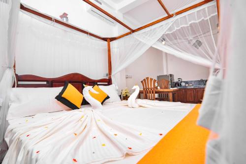 Schlafzimmer mit einem Bett mit weißer Bettwäsche und gelben Kissen in der Unterkunft VILLA RAY WHITE Unawatuna in Unawatuna
