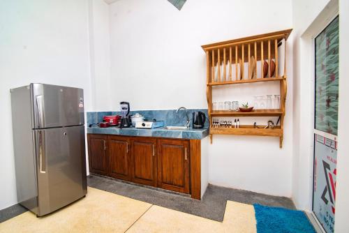 eine Küche mit Edelstahlkühlschrank und Holzschränken in der Unterkunft VILLA RAY WHITE Unawatuna in Unawatuna