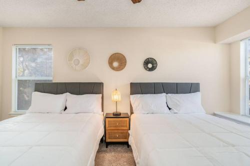two beds in a bedroom with white walls and windows at 3B Villa w Pool, BBQ, Firepit, Yard Games, Gym in San Antonio