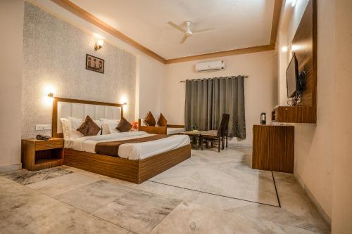 a bedroom with a bed and a desk and a television at Tripli Udaipur in Udaipur