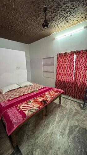 a bed sitting in a room with a red blanket at Radhika Palace Hotel in Pushkar