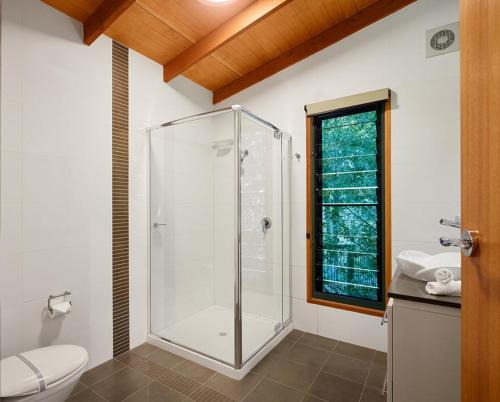 a bathroom with a shower and a toilet and a window at Dayboro Cottages in Dayboro