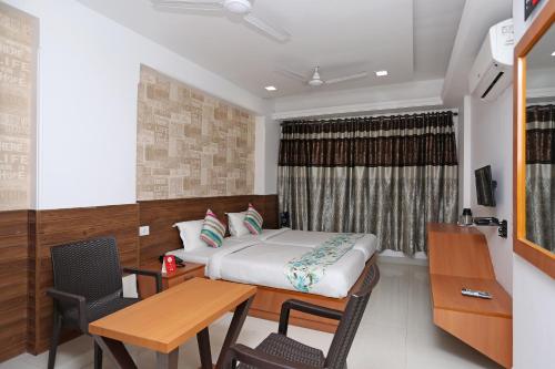 a bedroom with a bed and a desk and a table at OYO Hotel Grand Nishat in Patna