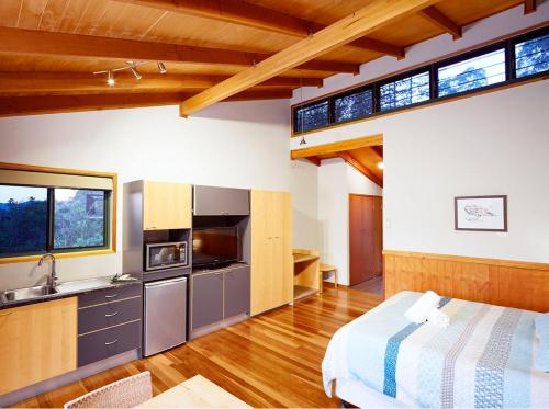 a room with a bed and a kitchen withwindows at Dayboro Cottages in Dayboro