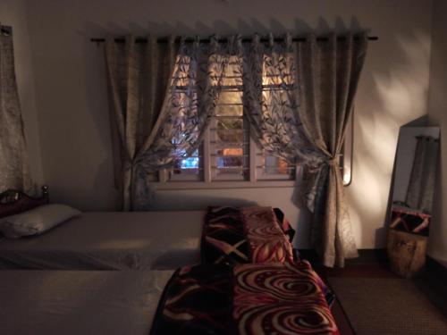a bedroom with a bed and a window with curtains at Assam Villa - by Storyweavers Retreat in Jorhāt