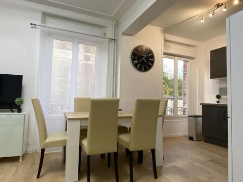 a dining room with a table and chairs and a clock at * L'appartement centre de Provins * ZEN LOC 4 in Provins