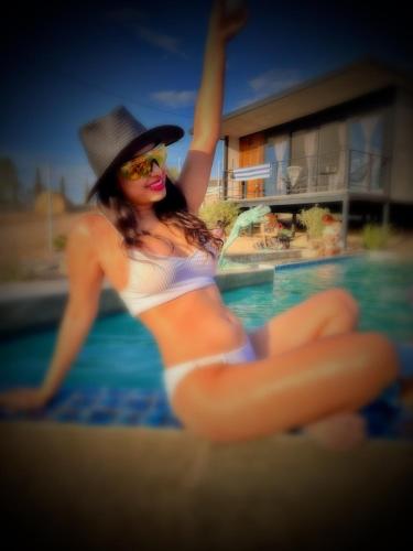 a woman in a bikini and hat next to a swimming pool at Finca Cazosa in Valle de Guadalupe