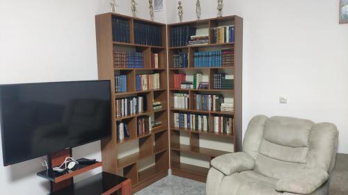 uma sala de estar com uma televisão e uma cadeira e prateleiras de livros em Apex rest house em Yerevan