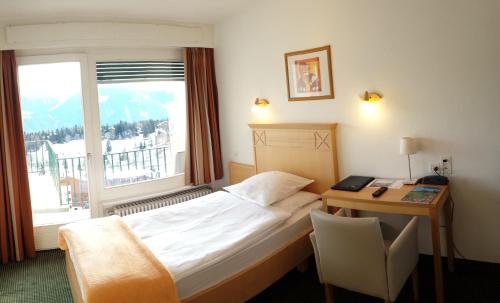 a hotel room with a bed and a desk and a window at Hôtel Splendide in Crans-Montana