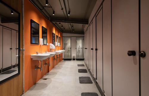 a bathroom with three sinks and orange walls at THE BAUHAUS in Mumbai