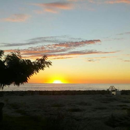 a sunset on the beach with the sun setting over the ocean at Aux 2 Métis in Toliara