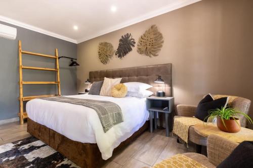 a bedroom with a large bed and a chair at Lowveld Living Guesthouse in Nelspruit
