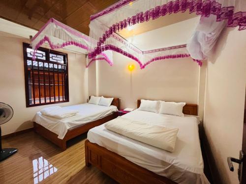 2 bedden in een kamer met paarse decoraties bij Homestay Bản Giốc- Tay's Traditional Village in Cao Bằng