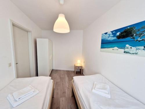 two beds in a white room with a painting on the wall at Luxury flat in the heart of Berlin 14 in Berlin