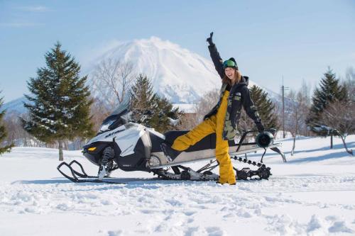 a man standing next to a snowmobile in the snow at Park Hyatt Niseko Hanazono in Kutchan