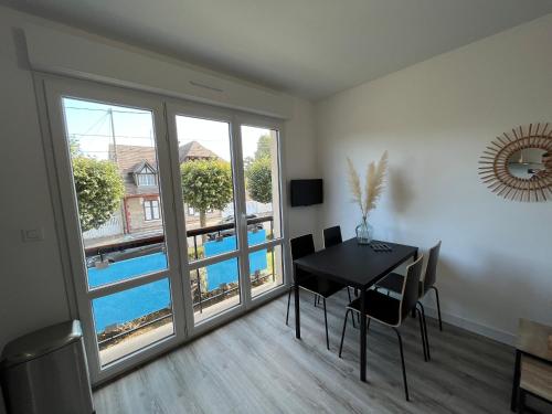 a dining room with a table and a large window at Jed YourHostHelper in Ouistreham