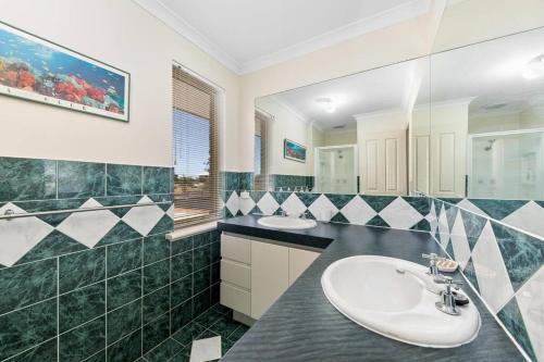 een badkamer met 2 wastafels en een spiegel bij Light & bright Falcon Bay family holiday escape in Mandurah