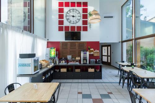 a restaurant with tables and a clock on the wall at Garden & City Lyon - Marcy in Marcy-lʼÉtoile